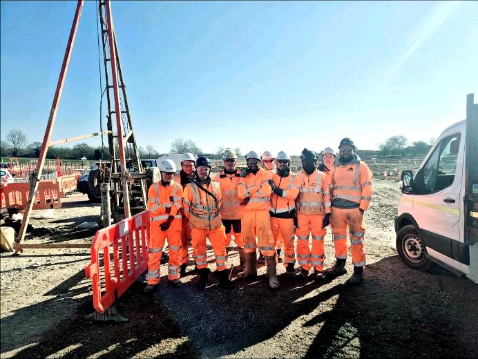Site investigation crew in orange PPE beside a cable percussion rig